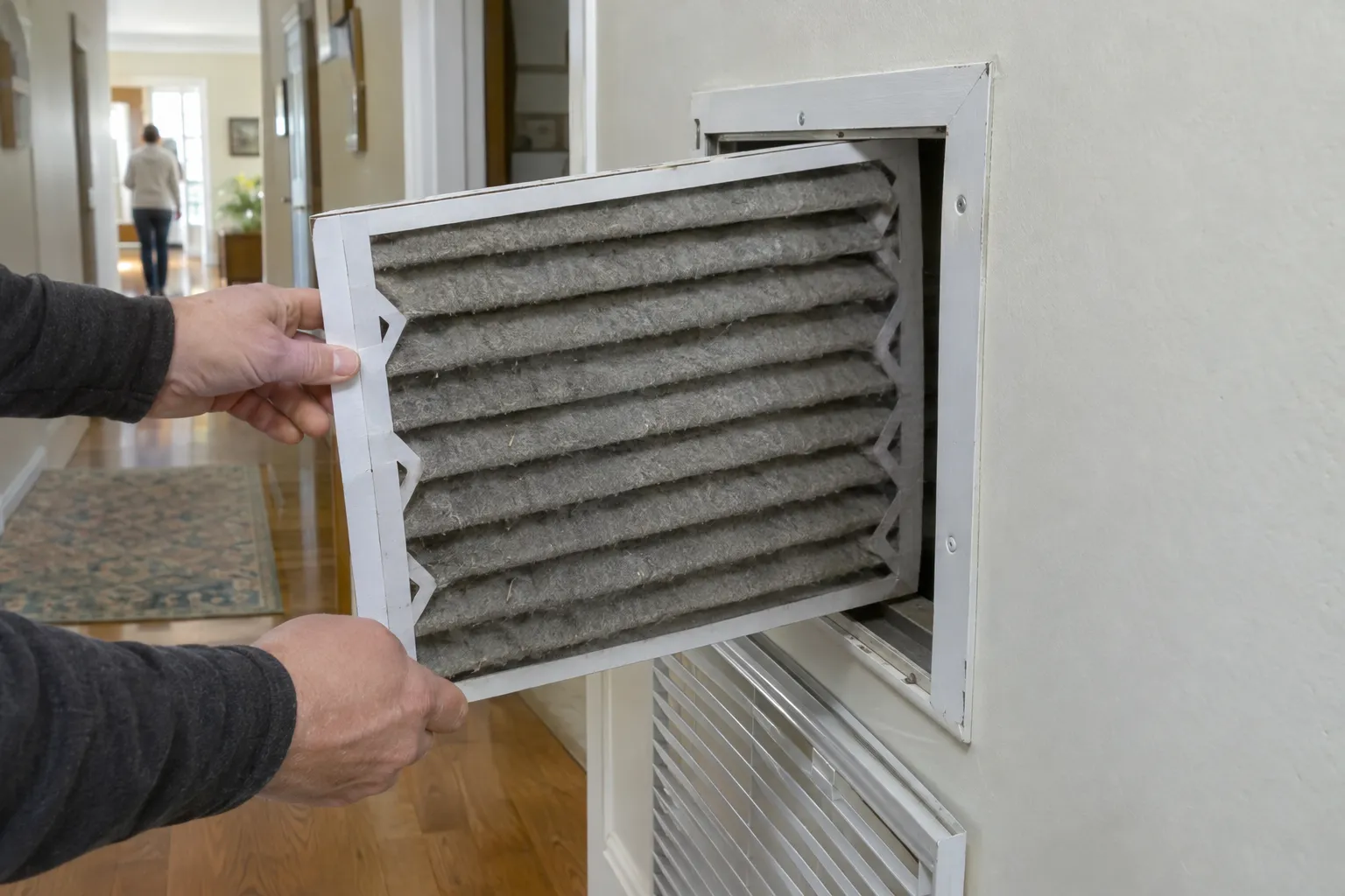 A dusty air filter being pulled out of a return air grille